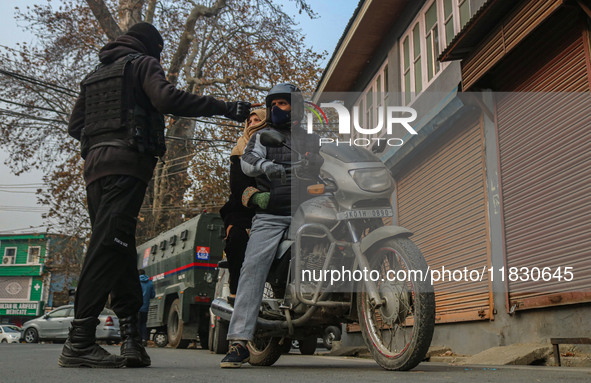 An Indian security personnel stops a motorcyclist during a gun battle between militants and security forces on the outskirts of Srinagar, Ja...