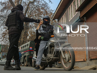 An Indian security personnel stops a motorcyclist during a gun battle between militants and security forces on the outskirts of Srinagar, Ja...