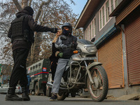 An Indian security personnel stops a motorcyclist during a gun battle between militants and security forces on the outskirts of Srinagar, Ja...