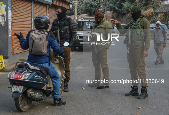 An Indian security personnel stops a motorcyclist during a gun battle between militants and security forces on the outskirts of Srinagar, Ja...