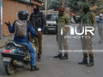 An Indian security personnel stops a motorcyclist during a gun battle between militants and security forces on the outskirts of Srinagar, Ja...