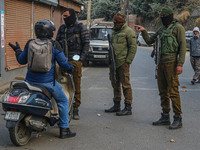 An Indian security personnel stops a motorcyclist during a gun battle between militants and security forces on the outskirts of Srinagar, Ja...