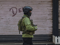 An Indian security personnel guards near the site of a gun battle between militants and security forces on the outskirts of Srinagar, Jammu...