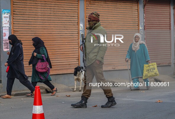 An Indian security personnel guards a road during a gun battle between militants and security forces on the outskirts of Srinagar, Jammu and...