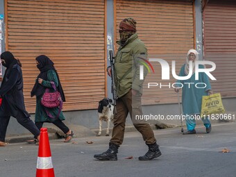 An Indian security personnel guards a road during a gun battle between militants and security forces on the outskirts of Srinagar, Jammu and...