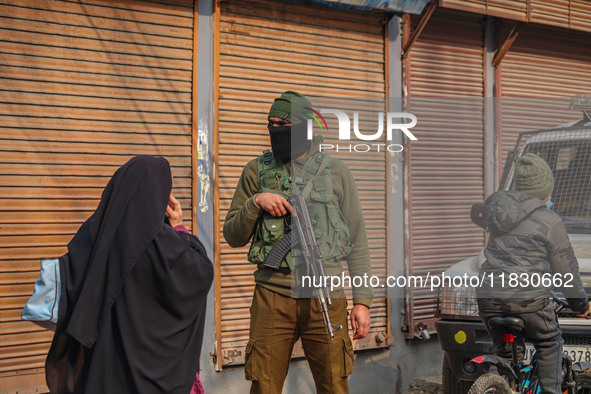 An Indian security personnel guards a road during a gun battle between militants and security forces on the outskirts of Srinagar, Jammu and...