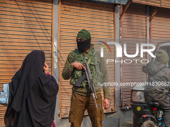 An Indian security personnel guards a road during a gun battle between militants and security forces on the outskirts of Srinagar, Jammu and...