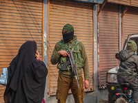 An Indian security personnel guards a road during a gun battle between militants and security forces on the outskirts of Srinagar, Jammu and...