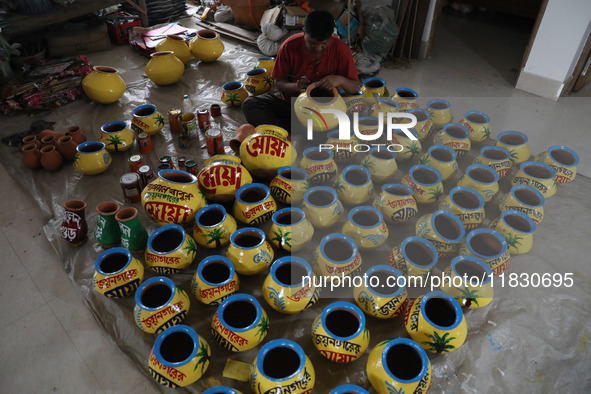 A vendor paints an earthen pot to store ''Joynagar Moa of West Bengal'' (an Indian sweet) made with folk rice mixed with date molasses insid...