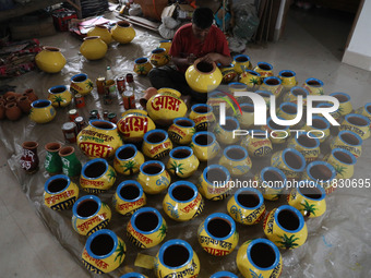 A vendor paints an earthen pot to store ''Joynagar Moa of West Bengal'' (an Indian sweet) made with folk rice mixed with date molasses insid...