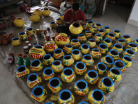 A vendor paints an earthen pot to store ''Joynagar Moa of West Bengal'' (an Indian sweet) made with folk rice mixed with date molasses insid...