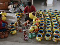 A vendor paints an earthen pot to store ''Joynagar Moa of West Bengal'' (an Indian sweet) made with folk rice mixed with date molasses insid...