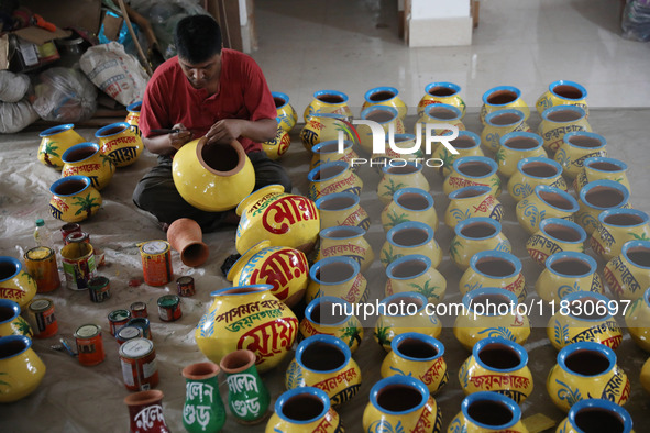 A vendor paints an earthen pot to store ''Joynagar Moa of West Bengal'' (an Indian sweet) made with folk rice mixed with date molasses insid...