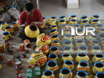 A vendor paints an earthen pot to store ''Joynagar Moa of West Bengal'' (an Indian sweet) made with folk rice mixed with date molasses insid...