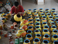 A vendor paints an earthen pot to store ''Joynagar Moa of West Bengal'' (an Indian sweet) made with folk rice mixed with date molasses insid...