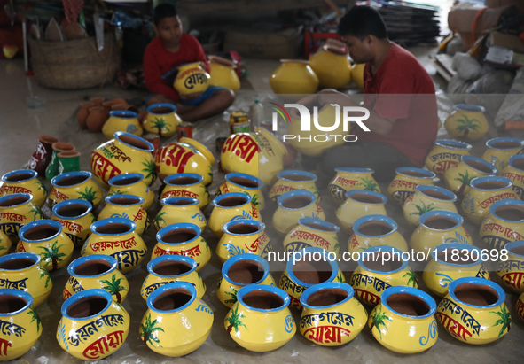 A vendor paints an earthen pot to store ''Joynagar Moa of West Bengal'' (an Indian sweet) made with folk rice mixed with date molasses insid...