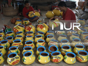 A vendor paints an earthen pot to store ''Joynagar Moa of West Bengal'' (an Indian sweet) made with folk rice mixed with date molasses insid...