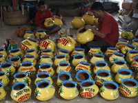 A vendor paints an earthen pot to store ''Joynagar Moa of West Bengal'' (an Indian sweet) made with folk rice mixed with date molasses insid...