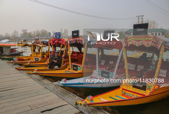 Abdul Razaaq, 70, sits next to Uber ''Shikaras'' or small boats after Uber launches its first water transport service on the waters of Dal L...