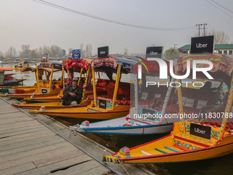 Abdul Razaaq, 70, sits next to Uber ''Shikaras'' or small boats after Uber launches its first water transport service on the waters of Dal L...