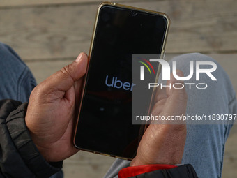 A man uses the Uber app after Uber launches its first water transport service on the waters of Dal Lake, in Srinagar, Jammu and Kashmir, on...