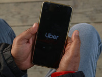 A man uses the Uber app after Uber launches its first water transport service on the waters of Dal Lake, in Srinagar, Jammu and Kashmir, on...