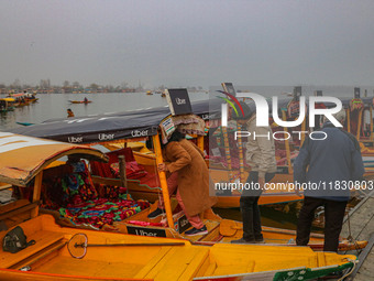 Indian tourists enter the Uber ''Shikara'' or small boat after Uber launches its first water transport service on the waters of Dal Lake, in...