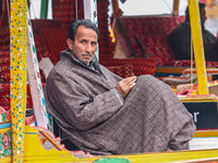 Abdul Rashid Bhat, 55, an Uber boat owner, sits outside his Shikara after Uber launches its first water transport service on the waters of D...