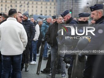 French Republicain Security Corps (CRS) officers face taxi drivers at the Invalides during a protest against lower mileage rates for patient...