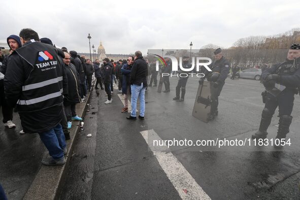 French Republicain Security Corps (CRS) officers face taxi drivers at the Invalides during a protest against lower mileage rates for patient...