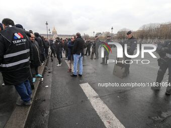 French Republicain Security Corps (CRS) officers face taxi drivers at the Invalides during a protest against lower mileage rates for patient...