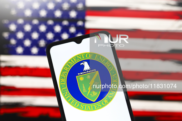 The United States Department of Energy (DOE) logo appears on the screen of a smartphone, and in the background, the flag of the United State...