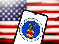 The United States Department of Labor (DOL) logo appears on the screen of a smartphone, and in the background, the flag of the United States...