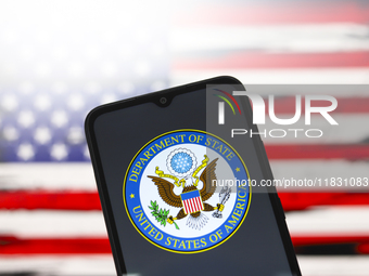 The United States Department of State (DOS) logo appears on the screen of a smartphone, and in the background, the flag of the United States...