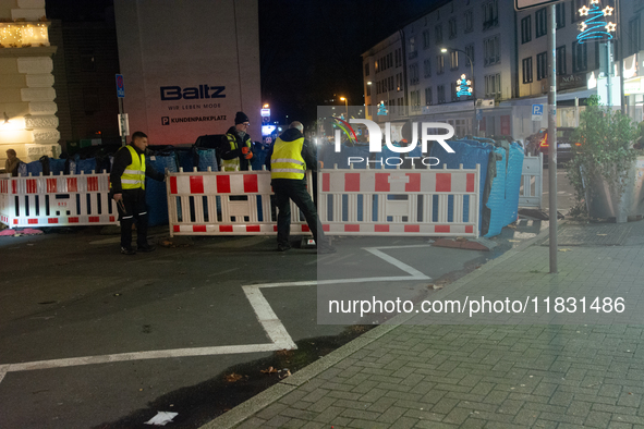 Several security workers reinstall the barriers at the closed Bochum Christmas market in Bochum, Germany, on December 3, 2024, as several la...