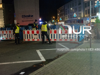 Several security workers reinstall the barriers at the closed Bochum Christmas market in Bochum, Germany, on December 3, 2024, as several la...