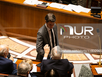 Former French Prime Minister Gabriel Attal shakes hands with Michel Barnier, French Prime Minister, during the questions to the National Ass...