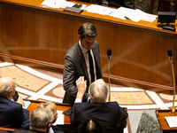 Former French Prime Minister Gabriel Attal shakes hands with Michel Barnier, French Prime Minister, during the questions to the National Ass...