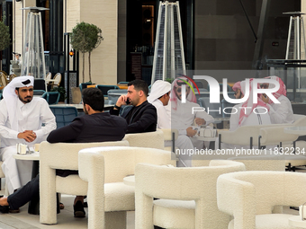 People sit outside a cafe in Downtown in the afternoon in Doha, Qatar, on December 03, 2024. (