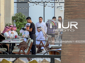 People sit outside a cafe in Downtown in the afternoon in Doha, Qatar, on December 03, 2024. (