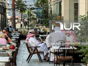 People sit outside a cafe in Downtown in the afternoon in Doha, Qatar, on December 03, 2024. (