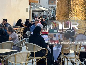 People sit outside a cafe in Downtown in the afternoon in Doha, Qatar, on December 03, 2024. (