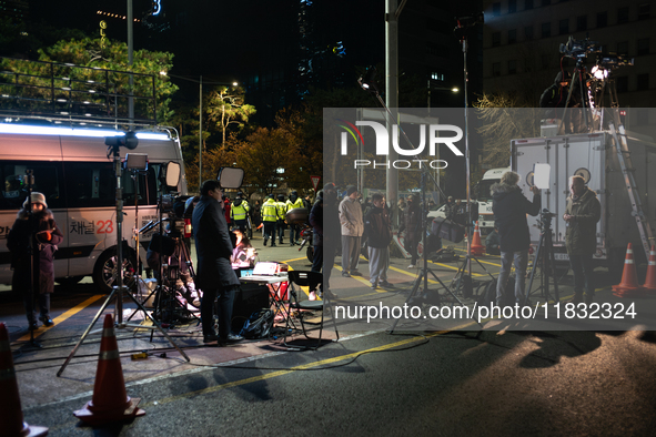 Media outlets prepare their reports outside the main gate of the National Assembly in Seoul, South Korea, on December 4, 2024, forming a hum...