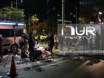 Media outlets prepare their reports outside the main gate of the National Assembly in Seoul, South Korea, on December 4, 2024, forming a hum...