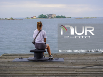 A single lady sits on the pier looking at the sea in Karlskrona, Sweden, on August 15, 2024. (