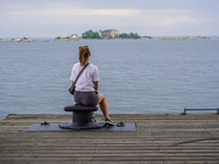 A single lady sits on the pier looking at the sea in Karlskrona, Sweden, on August 15, 2024. (