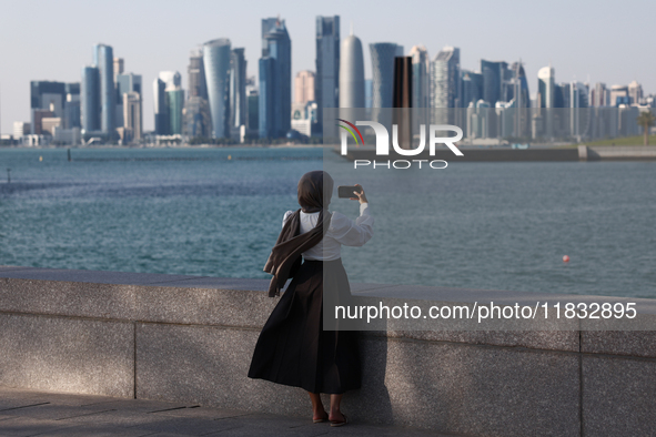 A woman wearing a scarf takes a photo in Doha, Qatar on December 3, 2024. 