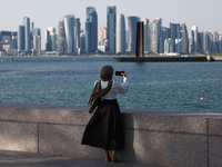 A woman wearing a scarf takes a photo in Doha, Qatar on December 3, 2024. (