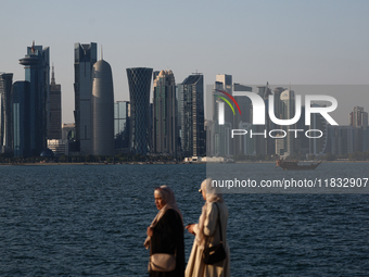 Women wearing traditional dress are seen with the city and Doha Bay in Doha, Qatar on December 3, 2024. (