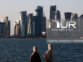 Women wearing traditional dress are seen with the city and Doha Bay in Doha, Qatar on December 3, 2024. (